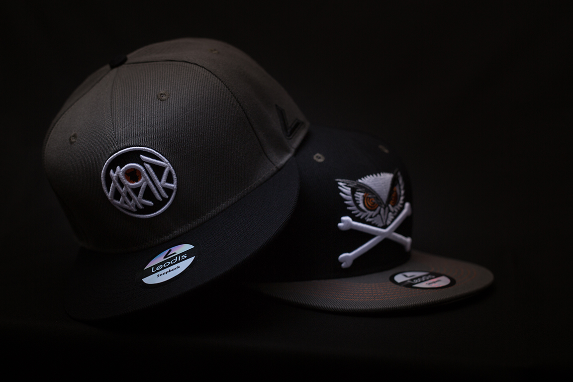 Two black snapback caps for men on a black background