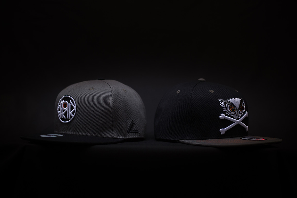 Two black snapback caps for men on a black background