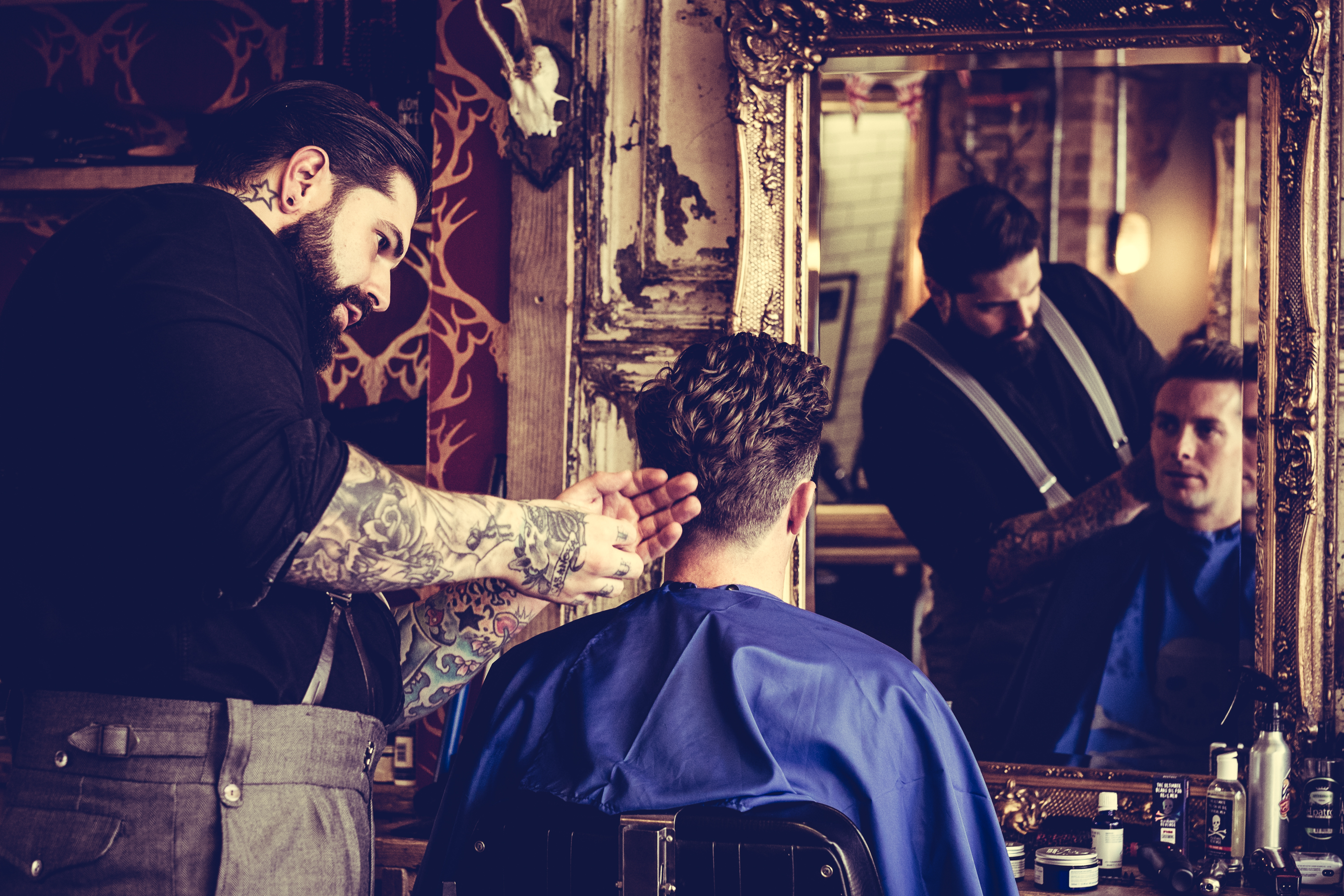 Young man in the barber's chair having his hair cut in front of a mirror