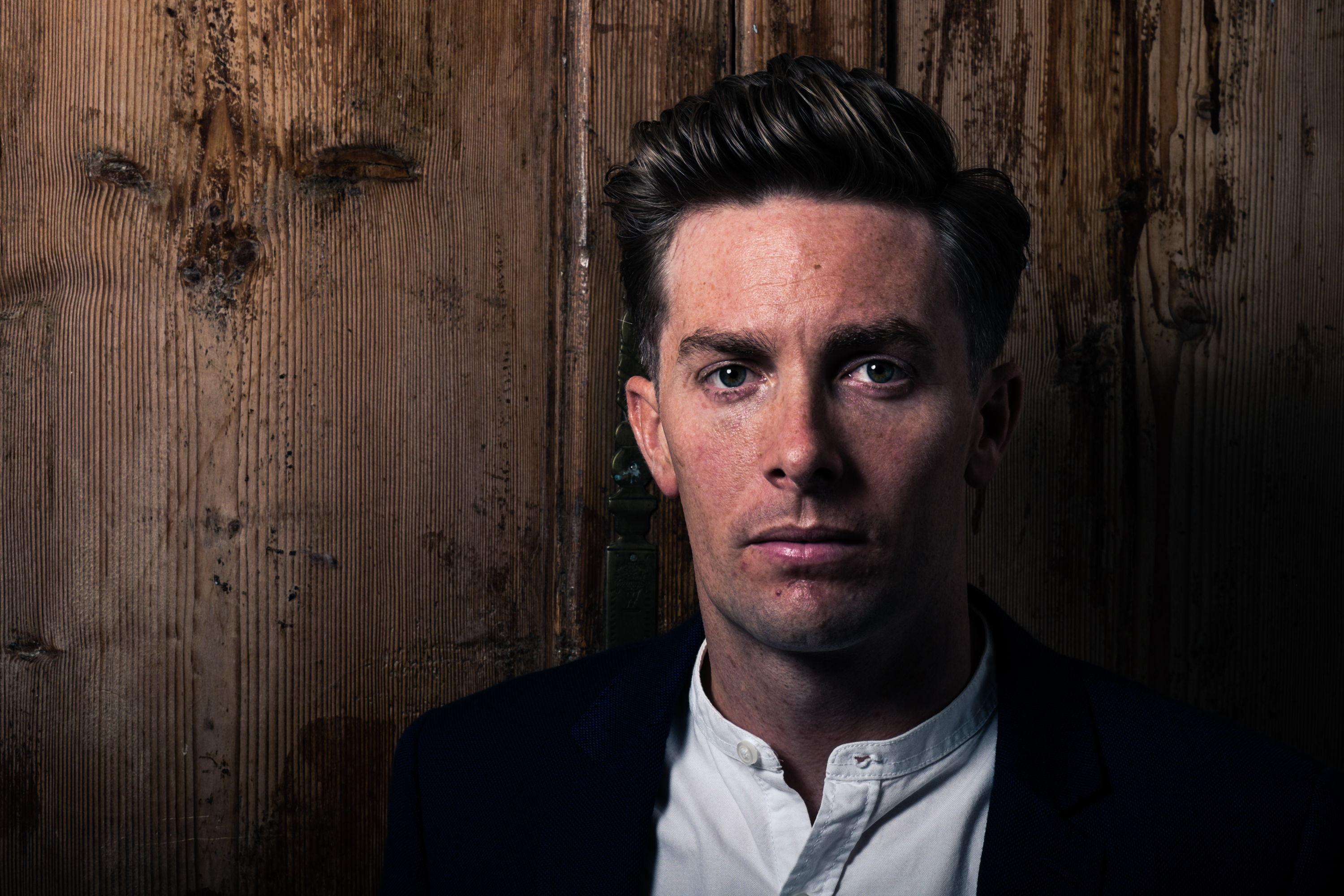 Dapper looking man in suit in front of wood background