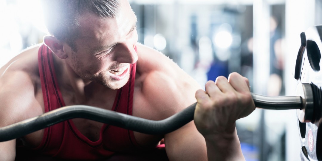 Man in gym lifting weights ahead of getting fit