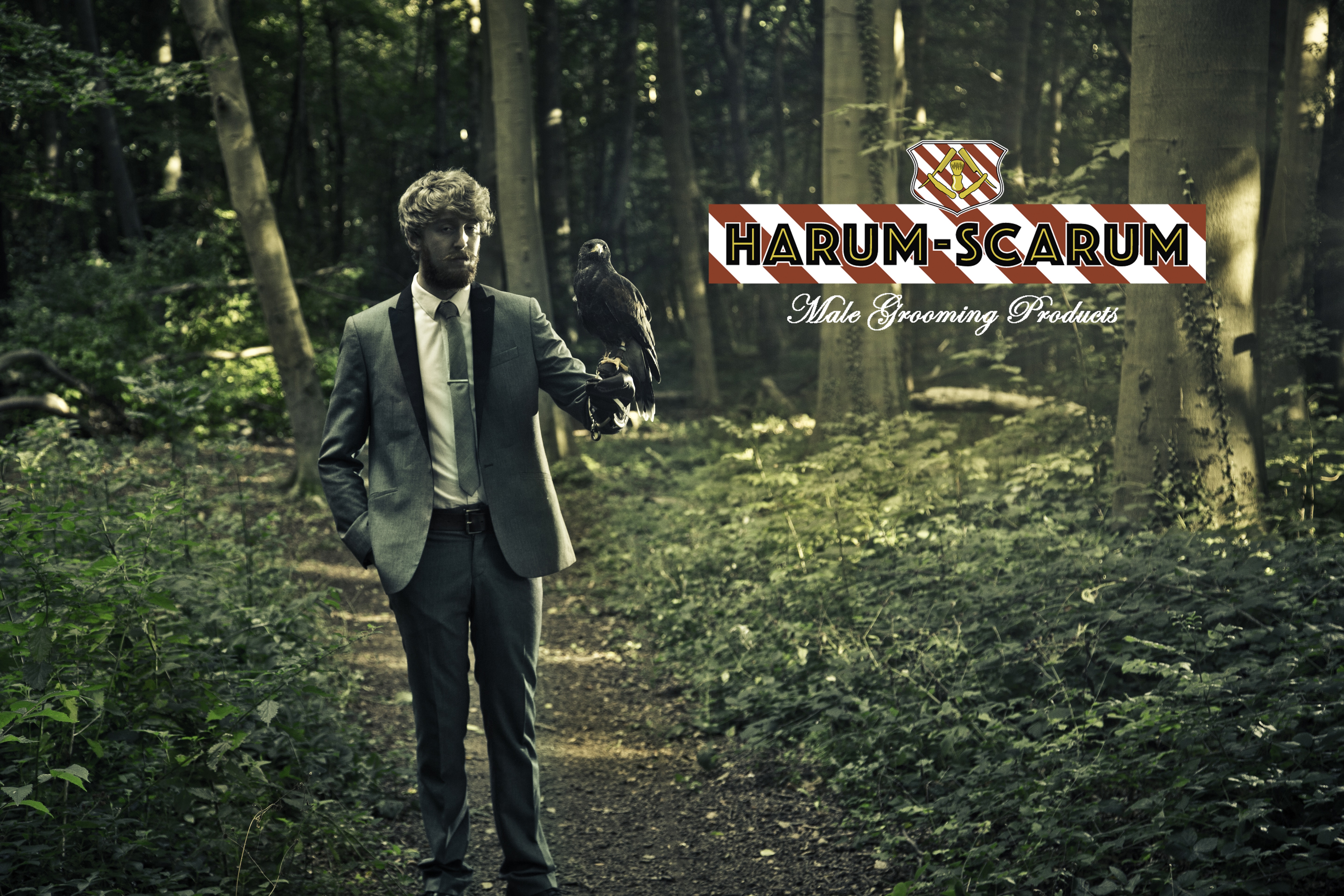 Man stood in forest in a suit with a bird of prey on his arm