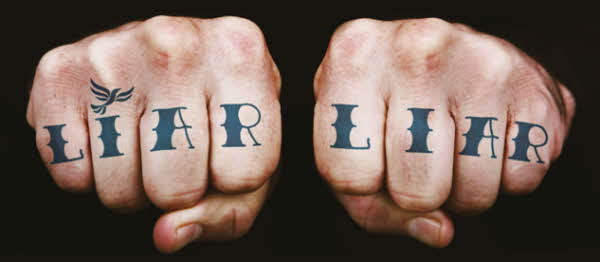 Man's hands with Liar Liar tattoo across knuckles with fist clench